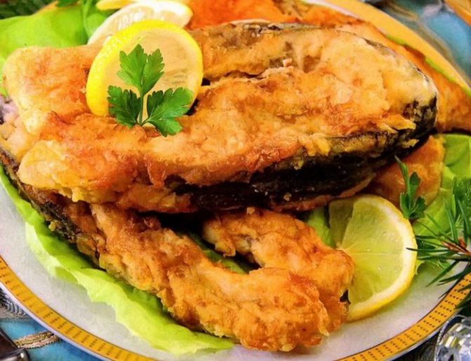 Карп жаренный, украшенный зеленью петрушки, лимоном
